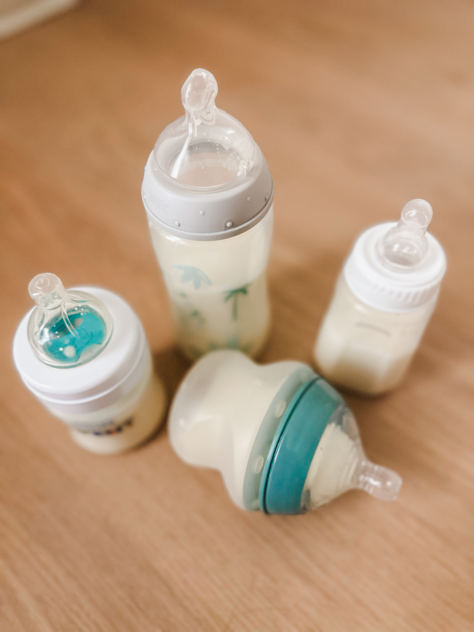 Four different baby bottles on a wood surface