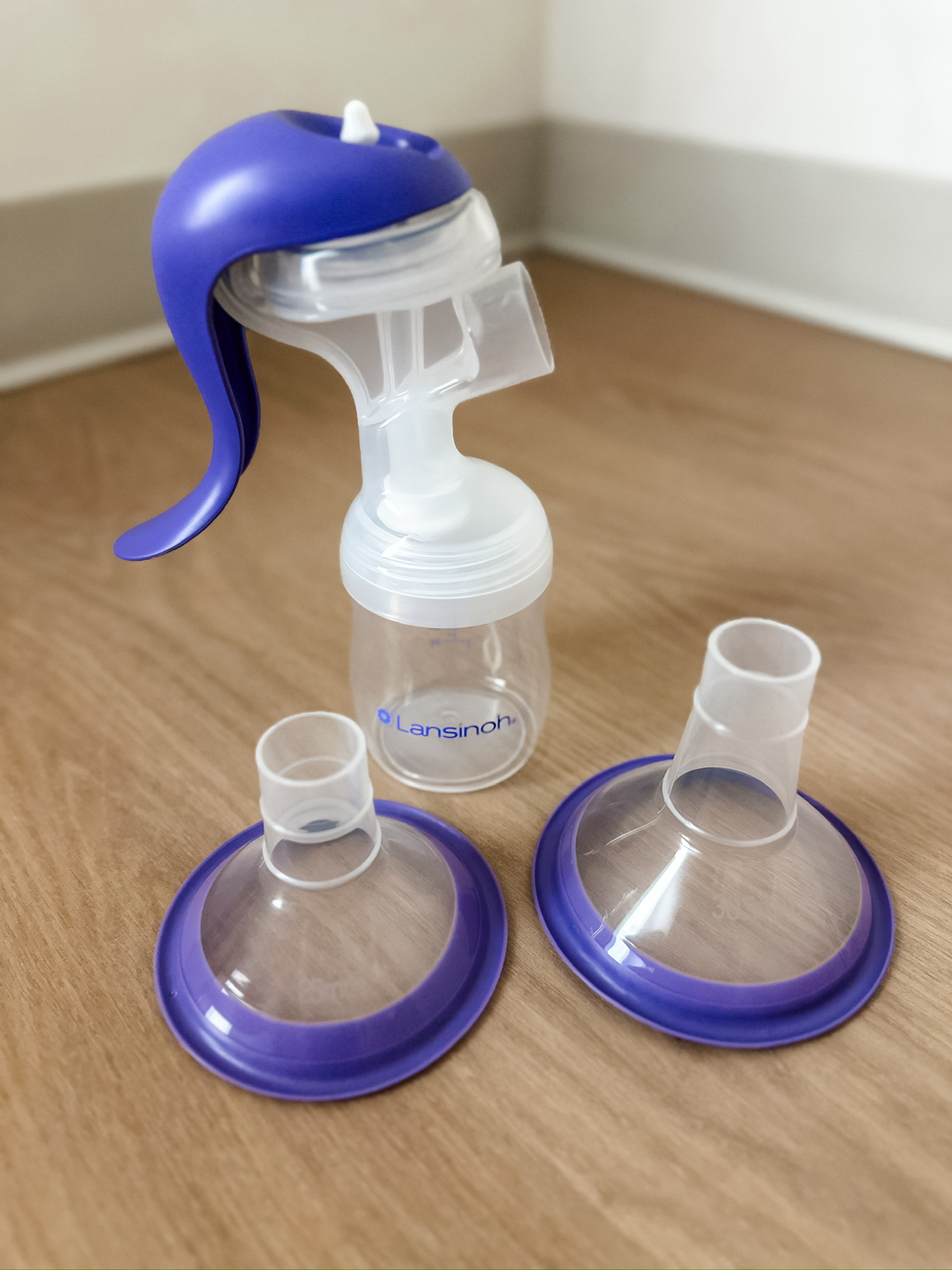 Manual breast pump with two breast pump flanges on a wood surface