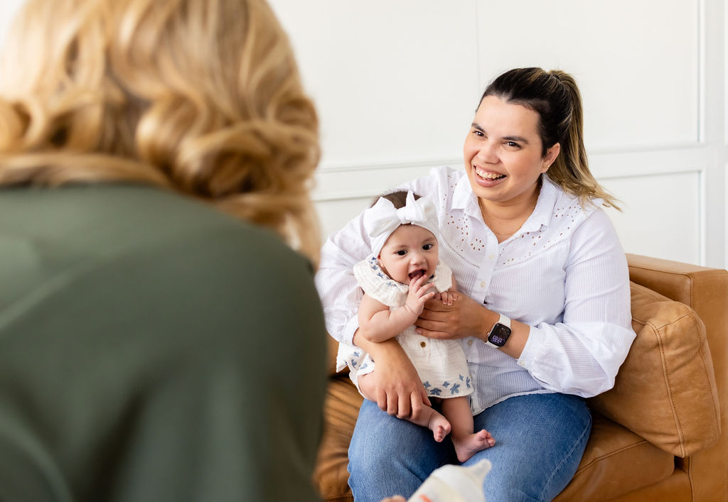 A caregiver holding an infant while talking with Ally Gore