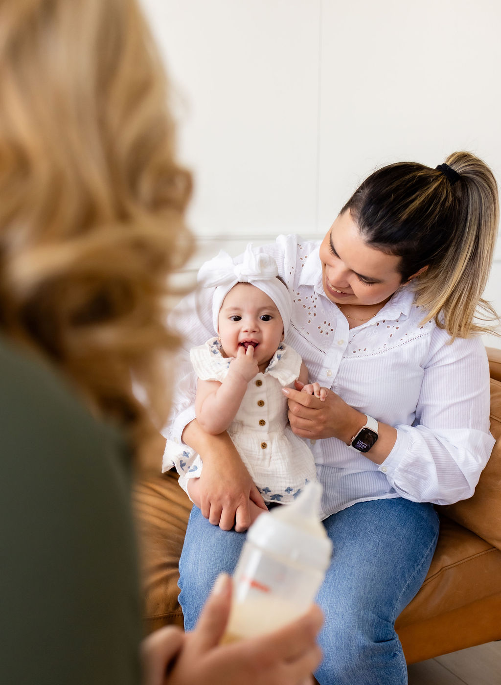 A caregiver holding an infant during a conversation with Ally Gore, who holds a bottle