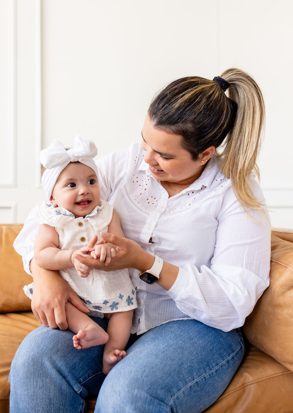 A caregiver smiling at an infant seated on her lap