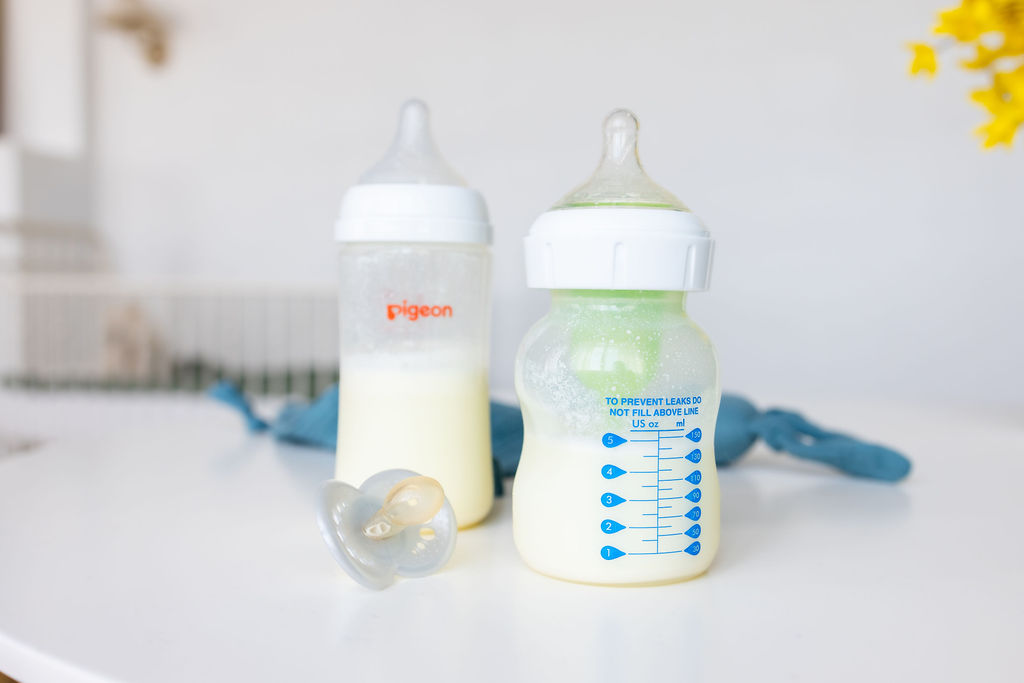 Two baby bottles and bottle nipples on a white surface