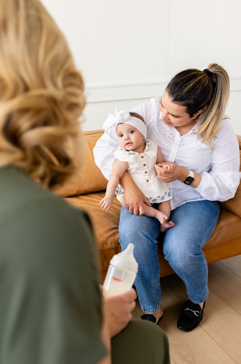 Ally Gore talking with a caregiver holding an infant, seen over the clinician's shoulder